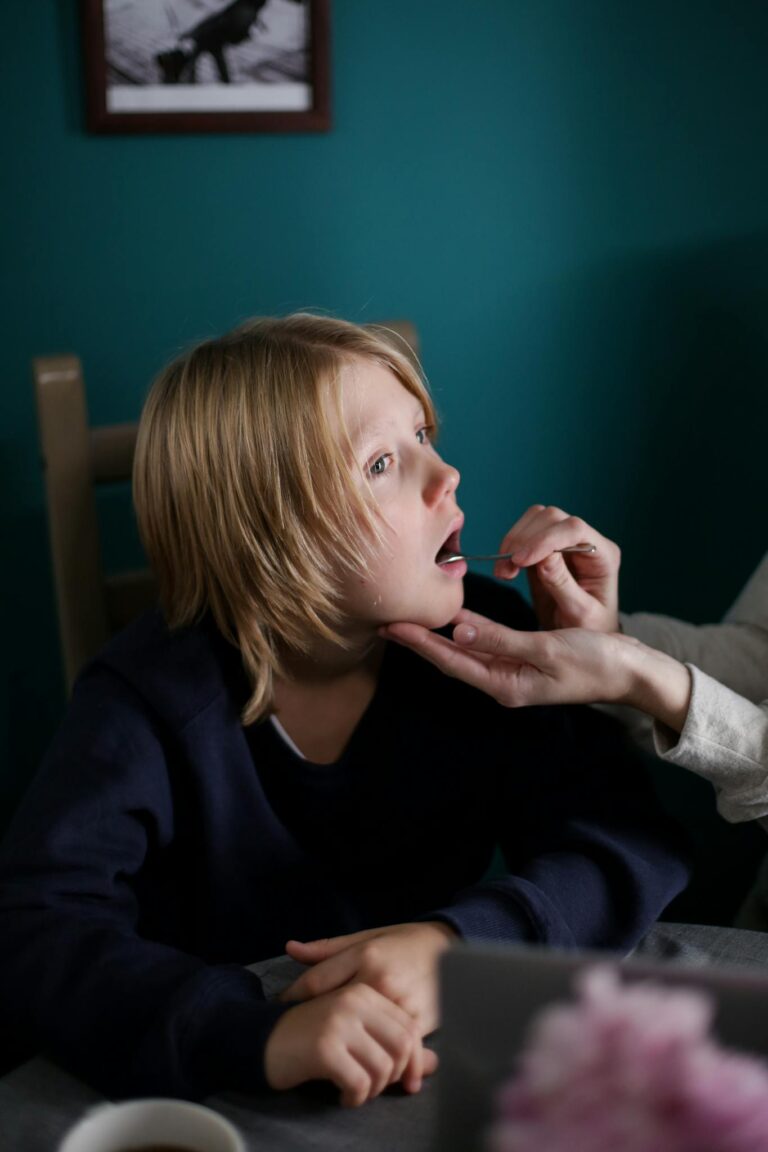 Young child being checked for illness symptoms indoors by a caregiver.